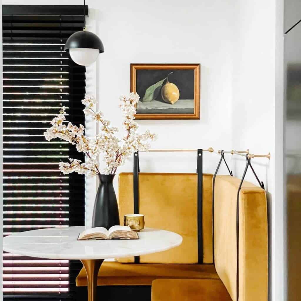 Framed picture of a lemon over a yellow cushioned bench.
