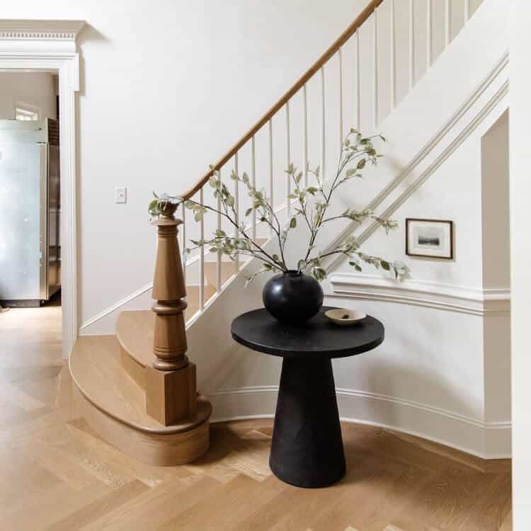 Charcoal pedestal table at the bottom of a staircase.