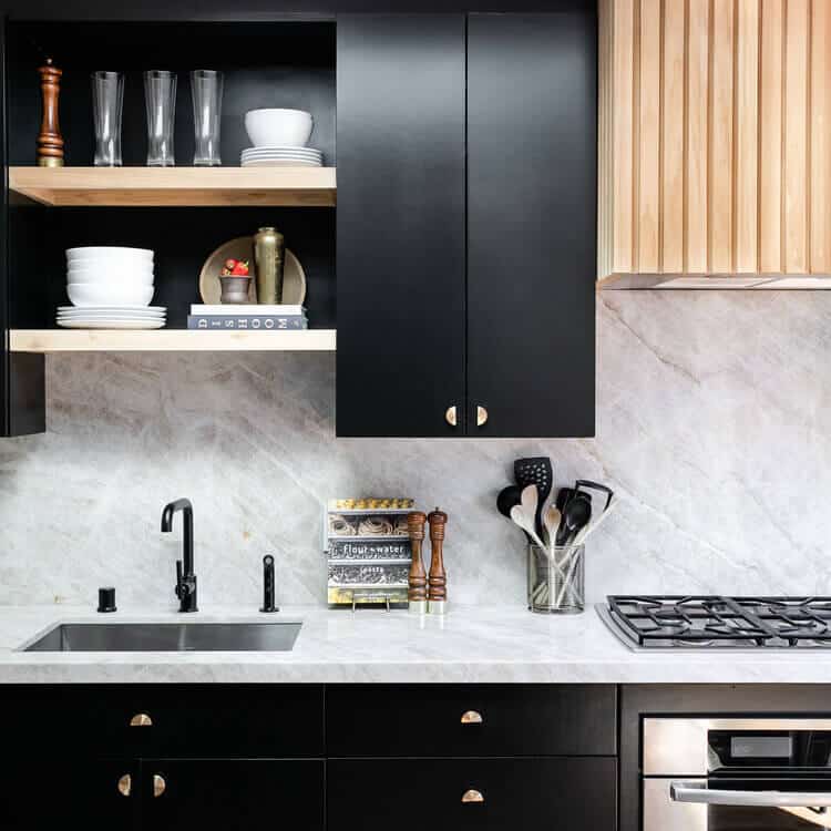 Kitchen with marbled countertops and black cabinets.