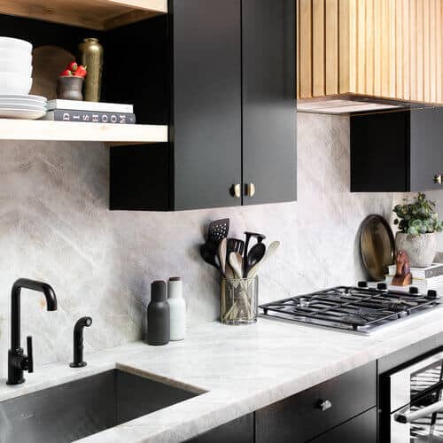Black kitchen cabinets with marbled countertop.