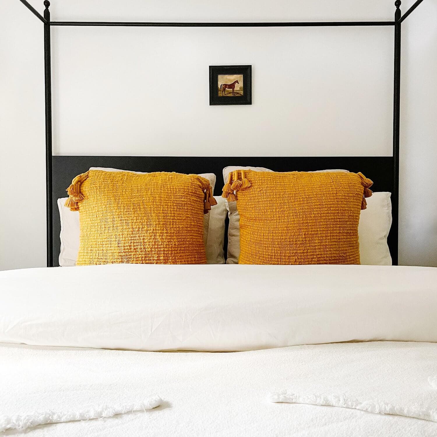 Golden throw pillows on a four poster bed.
