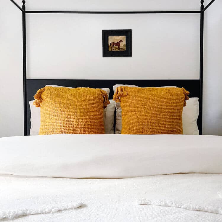 Tasseled saffron pillows on a white bed.