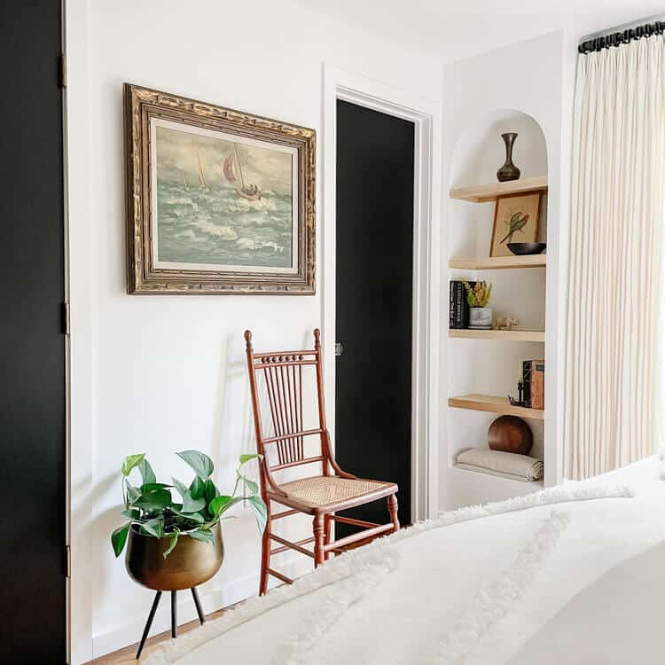 Art hanging on a wall over a chair and plant.