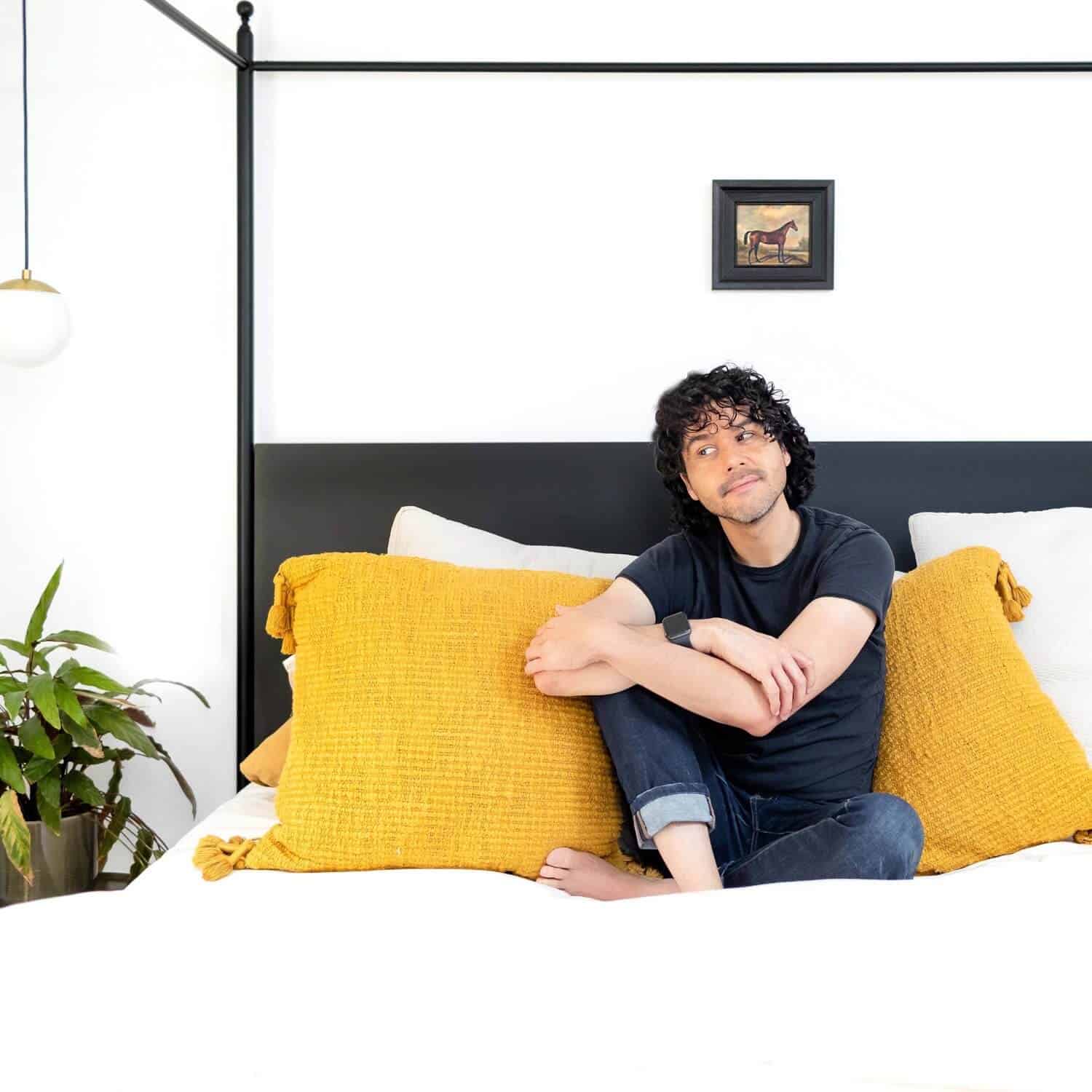Anthony sitting on a bed with yellow pillows.