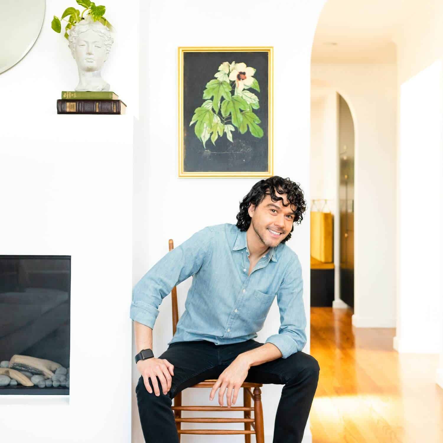 Anthony sitting under a framed picture of a plant.