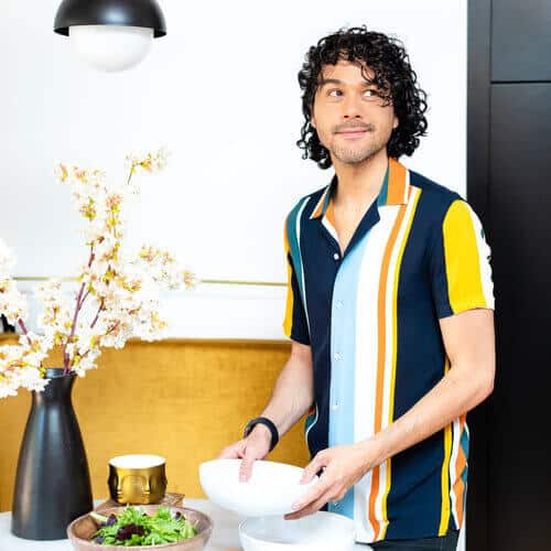 Anthony putting a bowl on a table with salad.