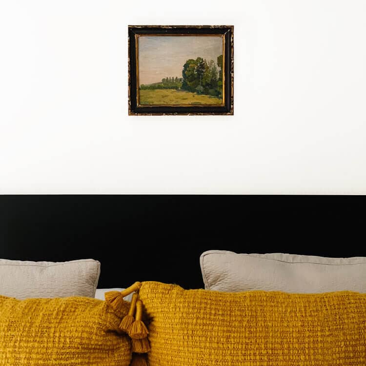 Framed landscape above a bed.