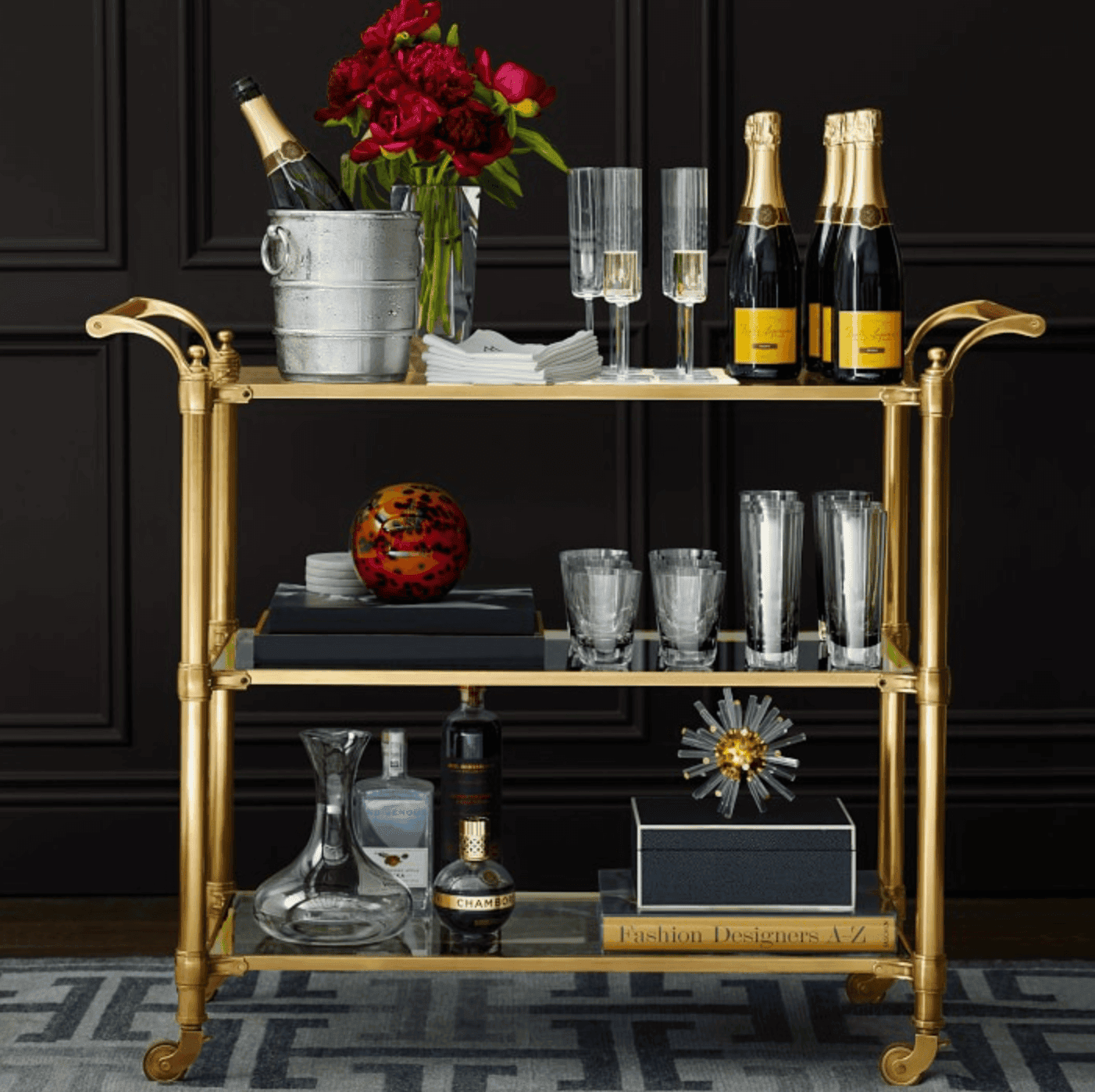 Golden bar cart filled with glassware and bottles.