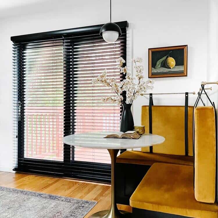 Blinds on a window next to a banquette.