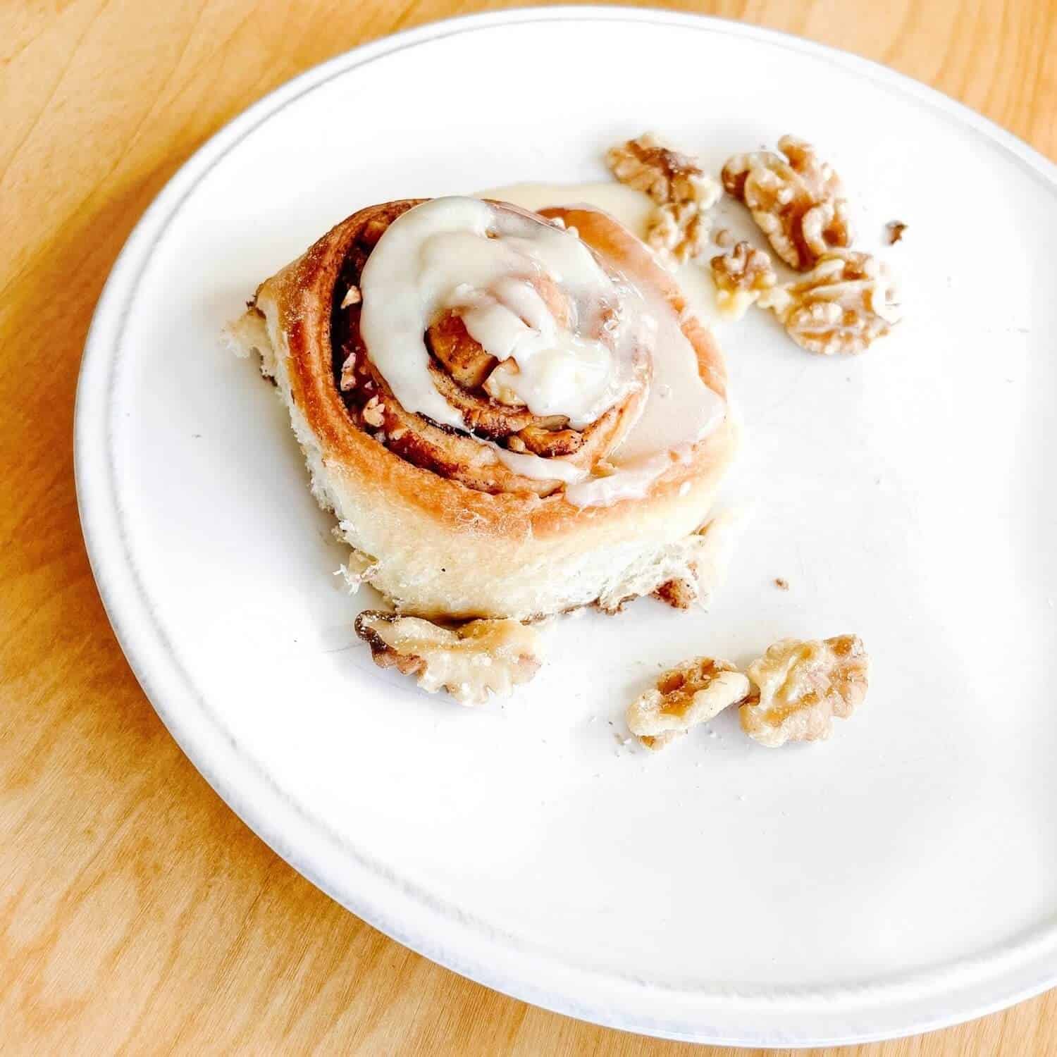 Cinnamon roll with frosting on a plate.