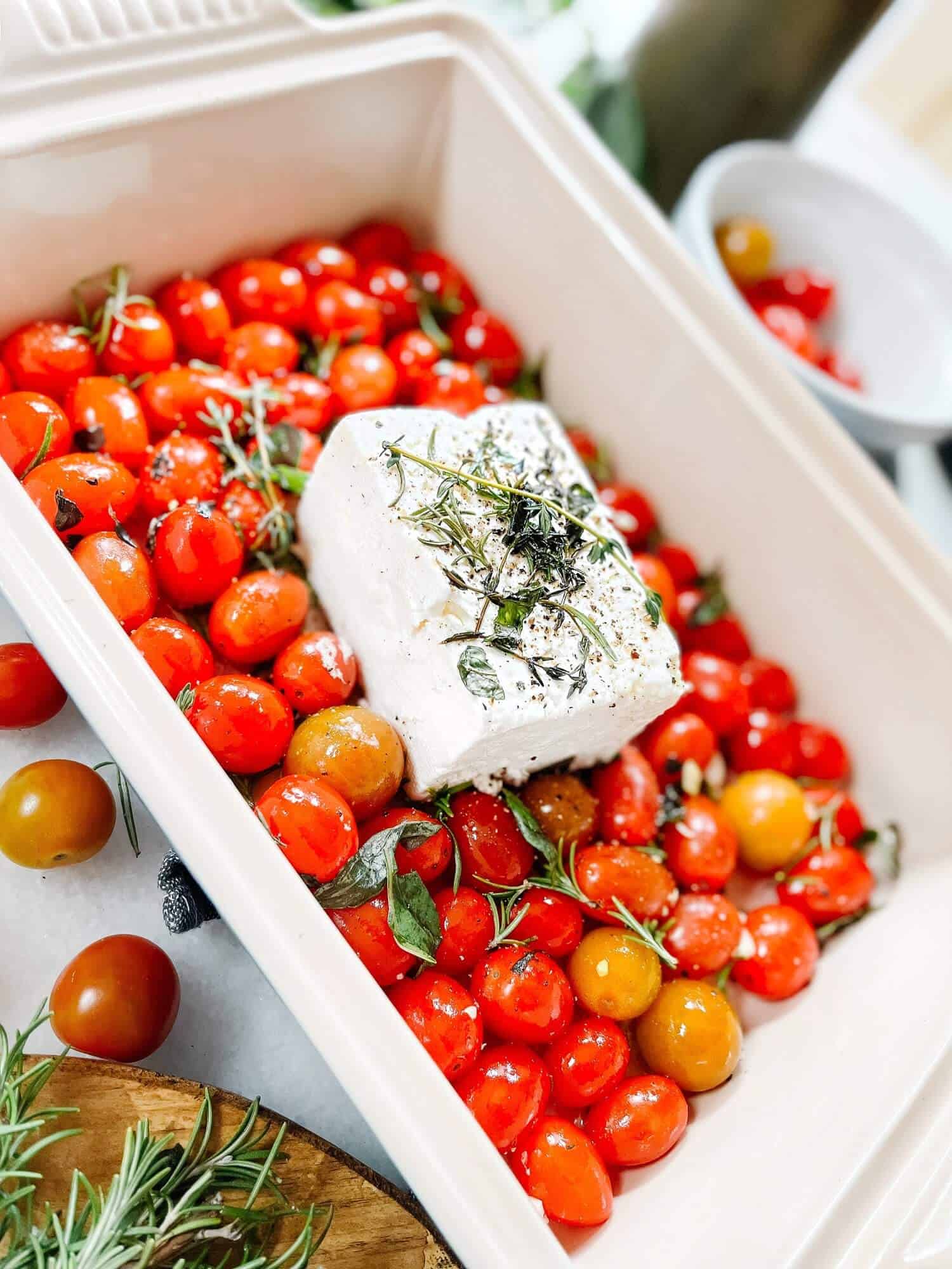 Feta topped with seasonings on a bed of tomatoes.