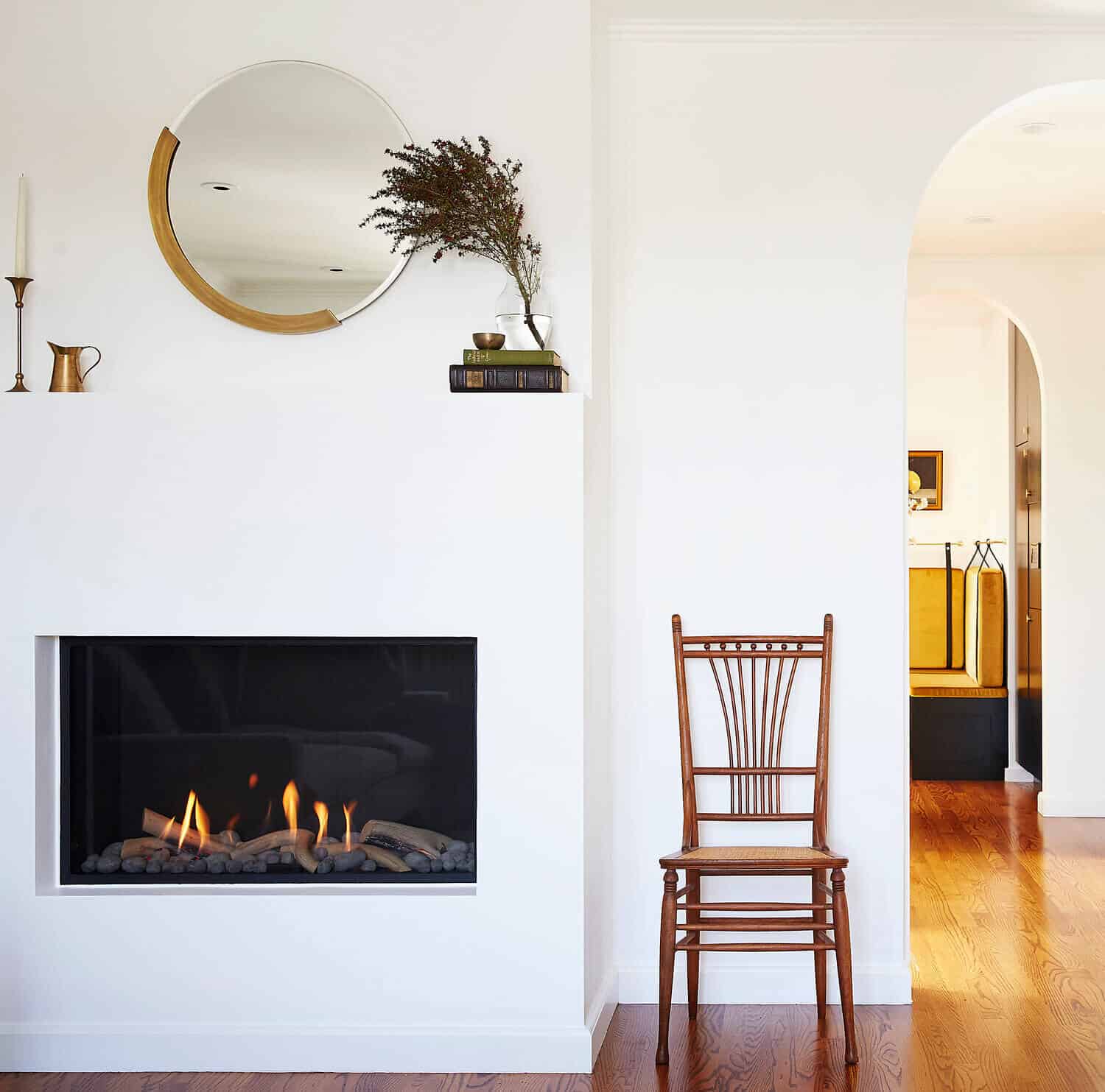 Gas fireplace in a white wall next to a chair.