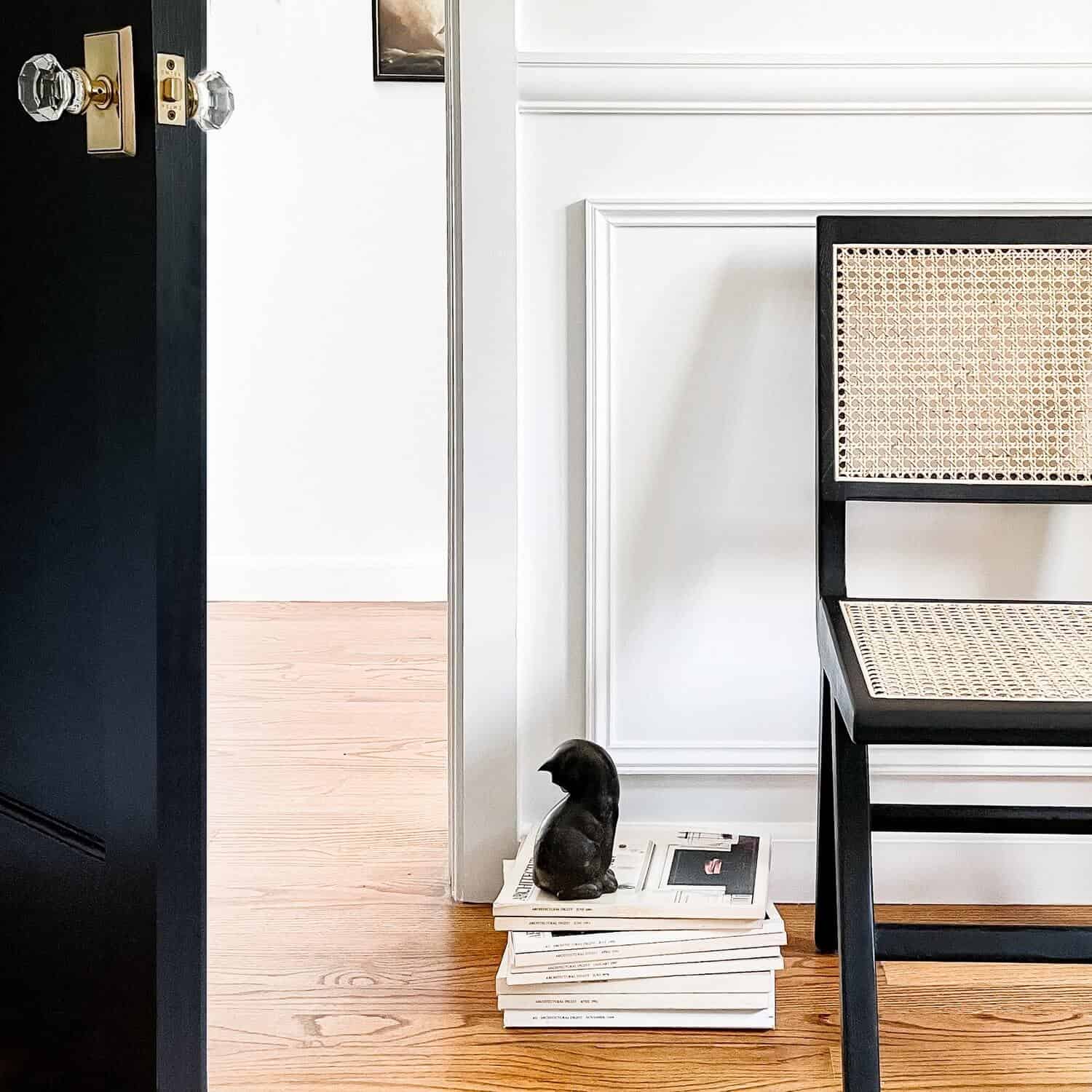 Black cat statue on a stack of magazines.