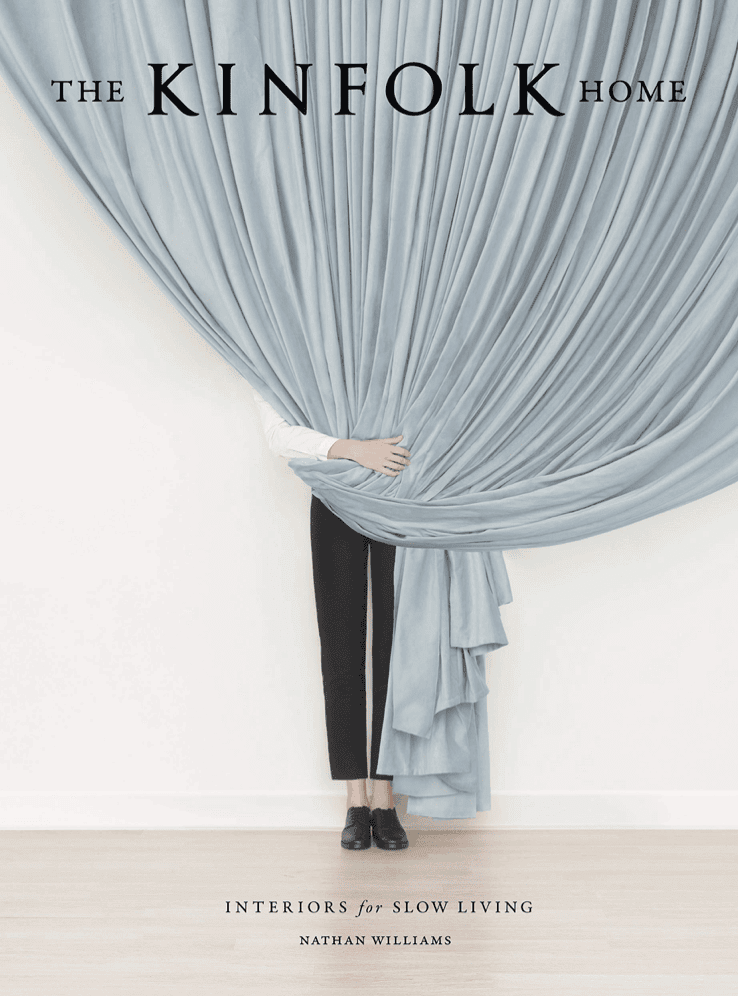 Person behind a curtain on the cover of a book titled \"The Kinfolk Book.\"