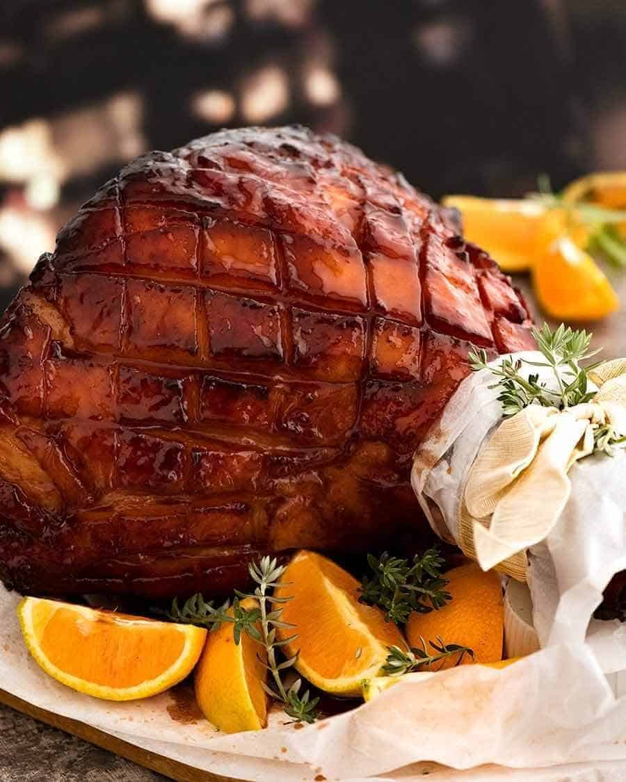 Maple glazed ham with orange wedges.