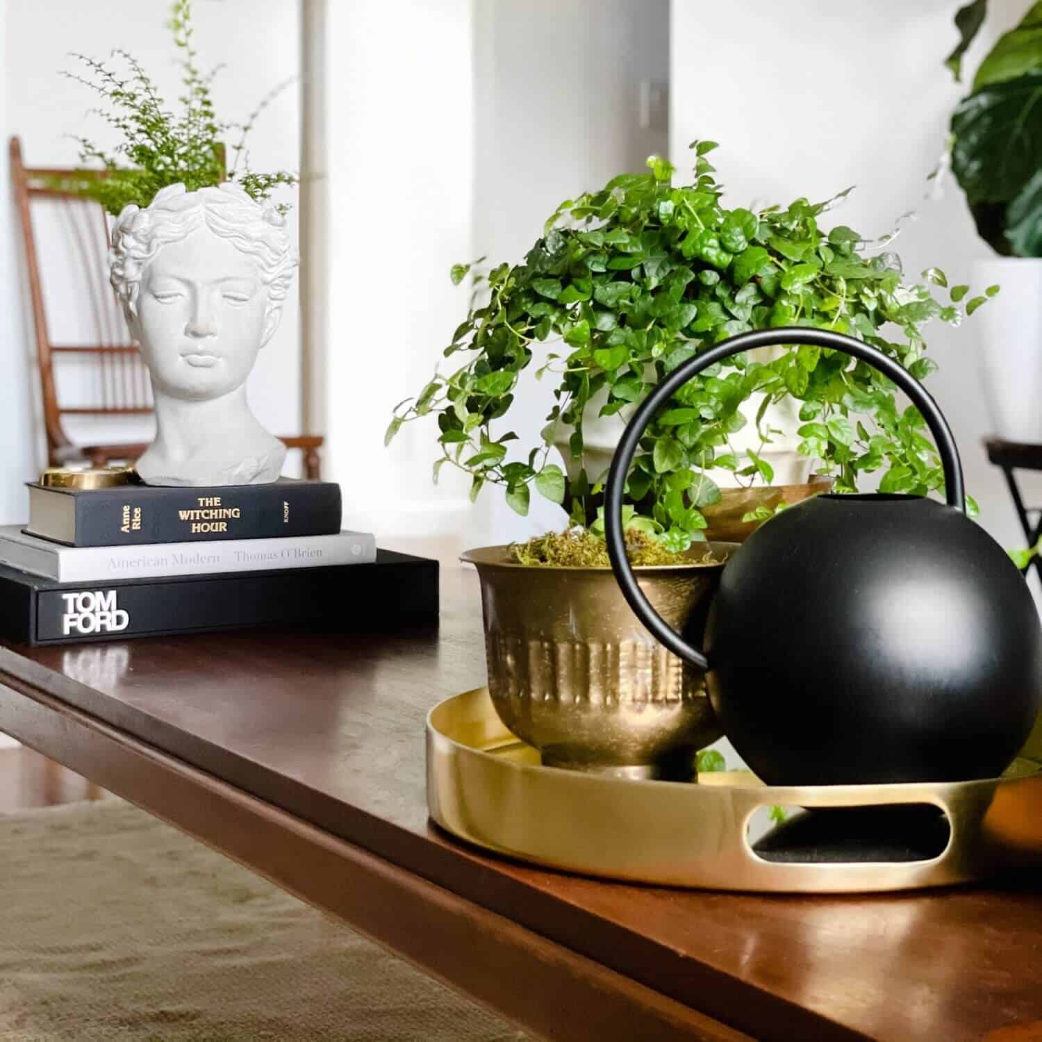 Coffee table topped with books and a golden tray.
