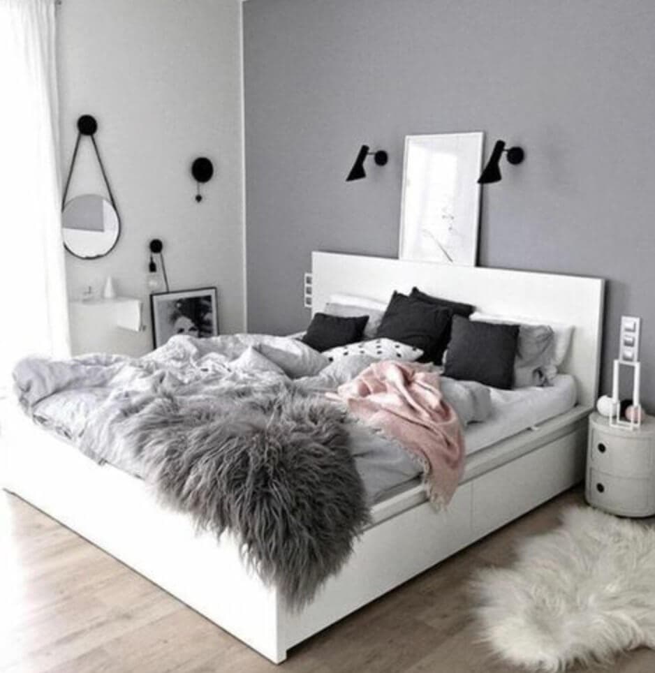 Grey room with a bed covered in various blankets.