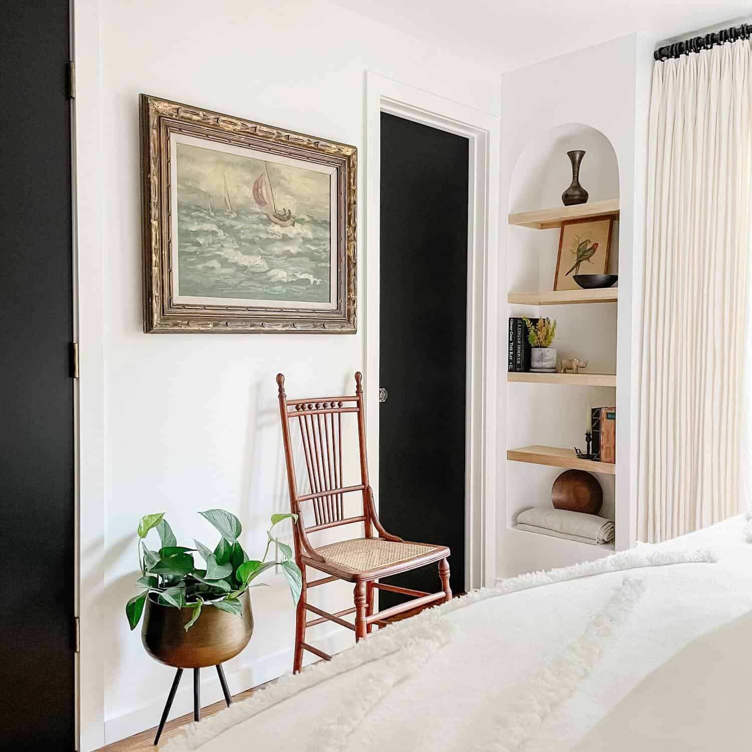 Arched bookshelf, chair, and plant in a room with white walls.