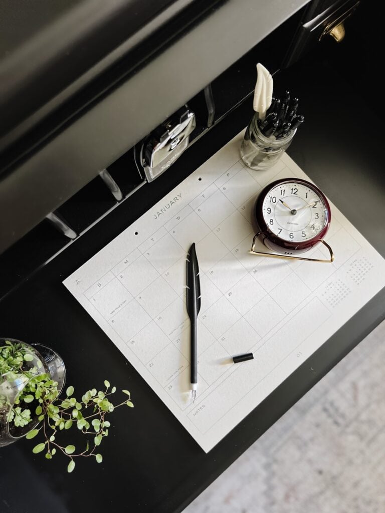 Large monthly calendar on a black desk.