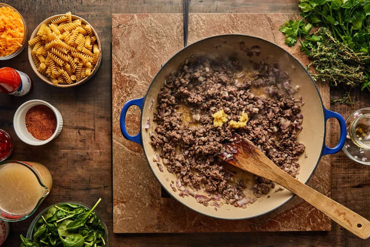  The cooking process shows ground beef being browned in a skillet with onions and garlic.

