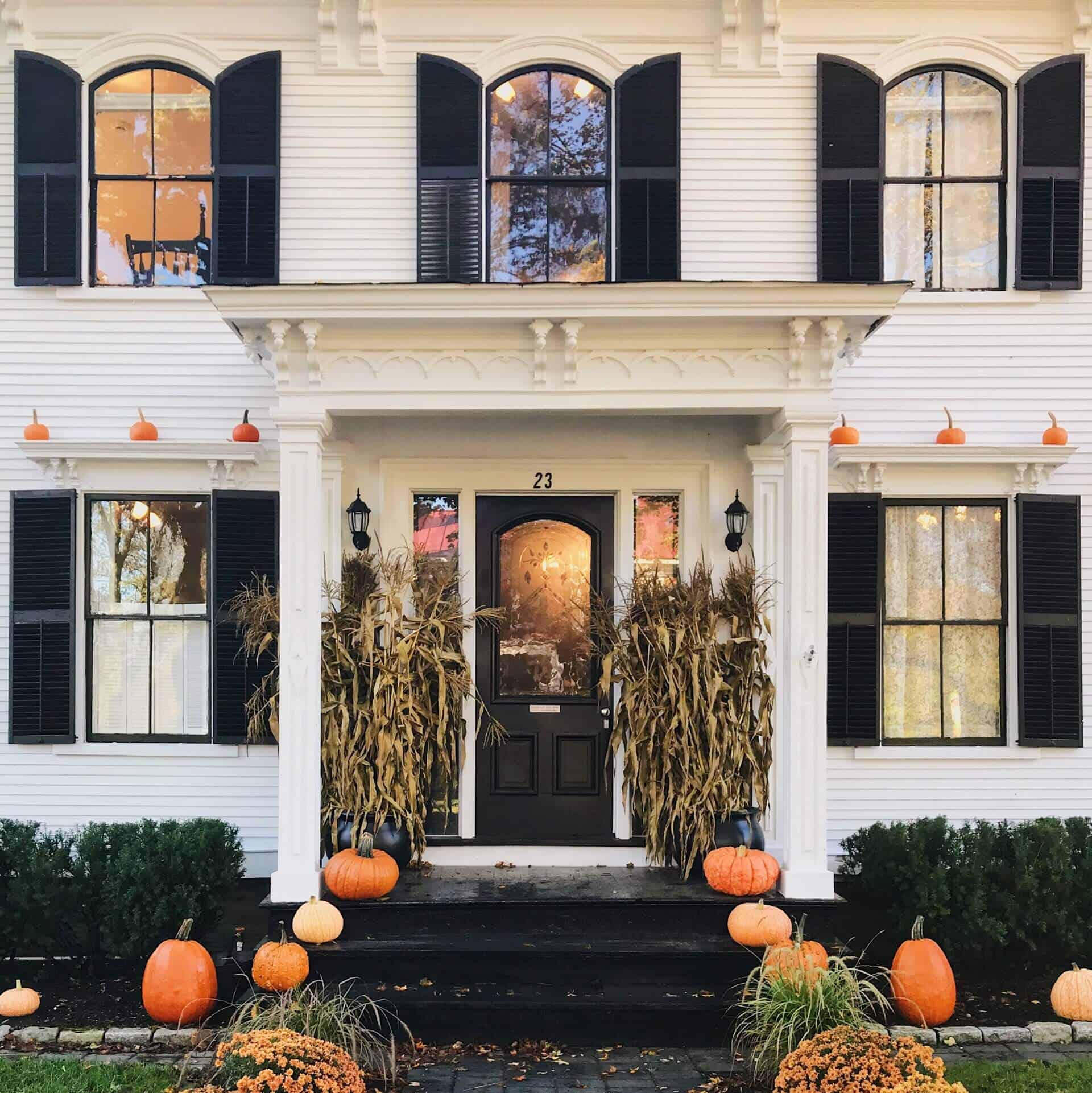 House exterior decorated with pumpkins, mums, and other fall decor.