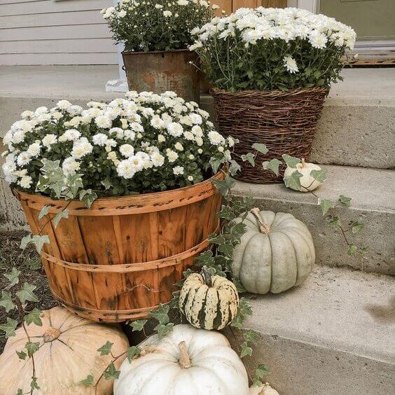 Baskets and planters with muted flowers and pumpkins.