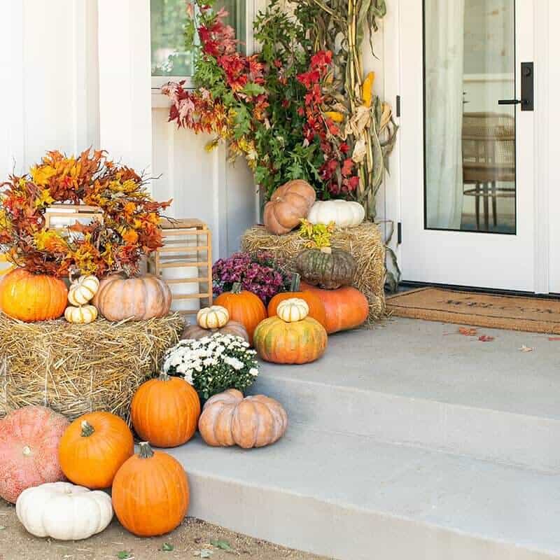 Pumpkins of different colors and sizes on a front step.