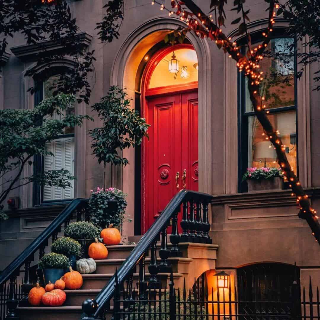 Pumpkins on steps in front of a red door.