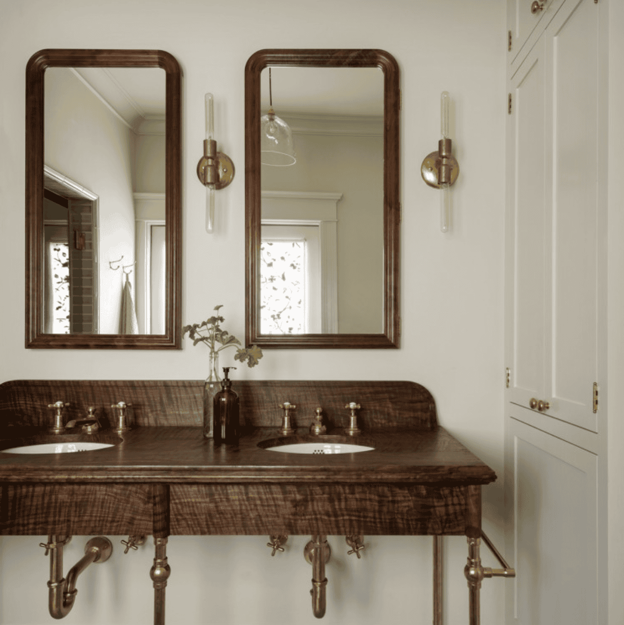 Wooden vanity and mirrors with bronze fixtures and lights.