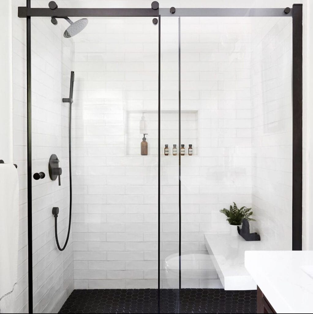 Glass shower enclosure with white tile walls.