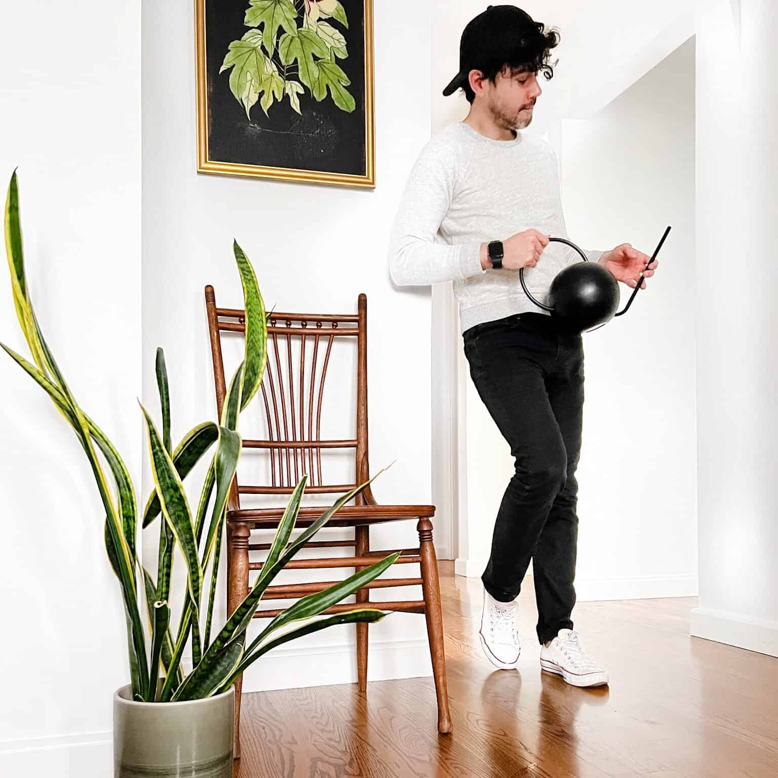 Man holding a watering can in a room with a snake plant.