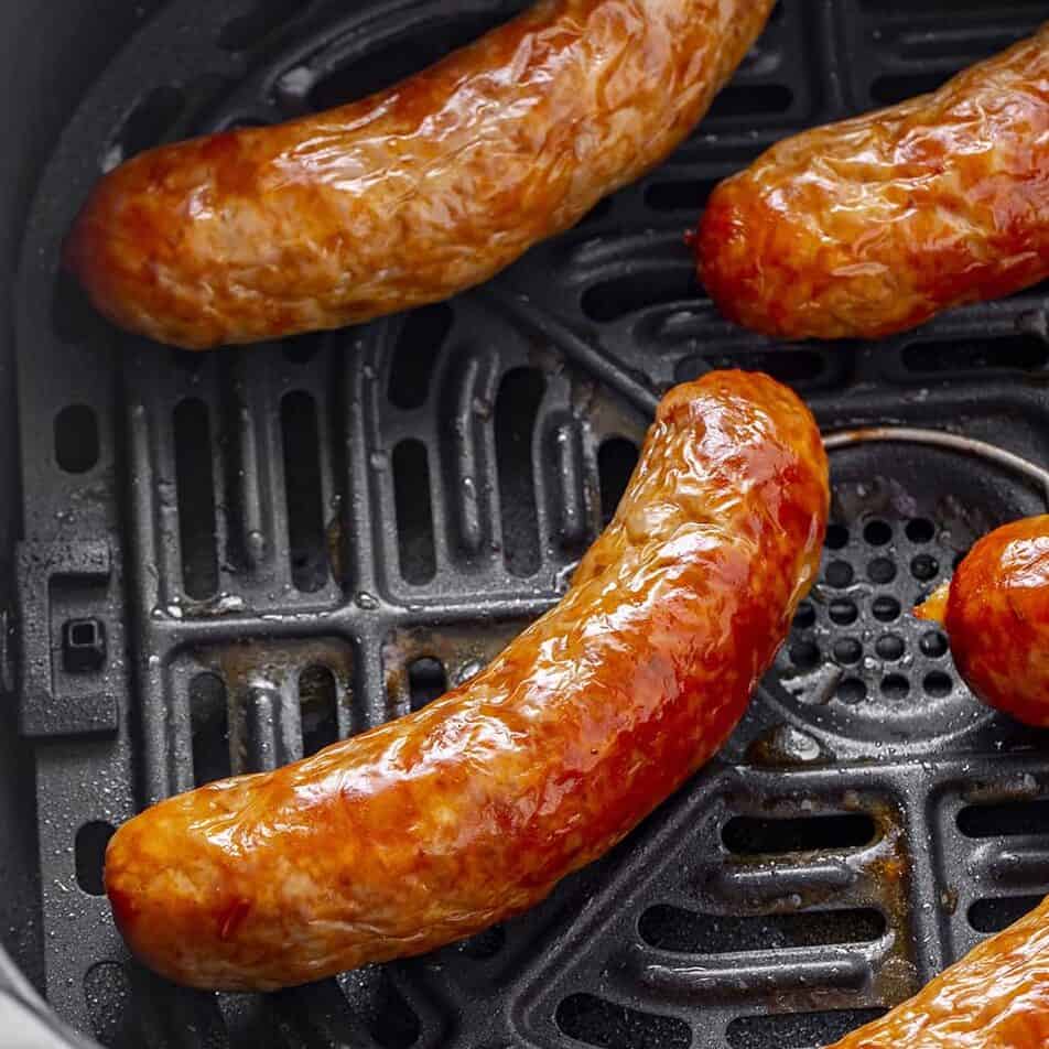 Sausages in an Air Fryer basket.