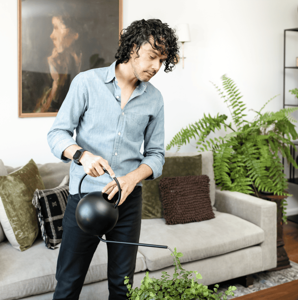 Anthony watering plants in the living room.