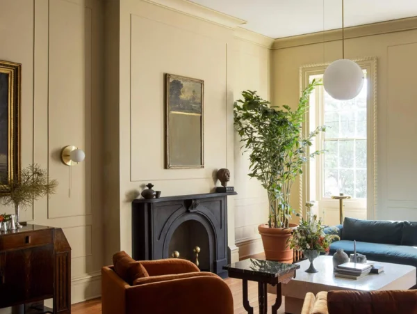 types of lighting in a gorgeous art deco room with a black stone fireplace, deep orange velvet accent chair and textured decor.