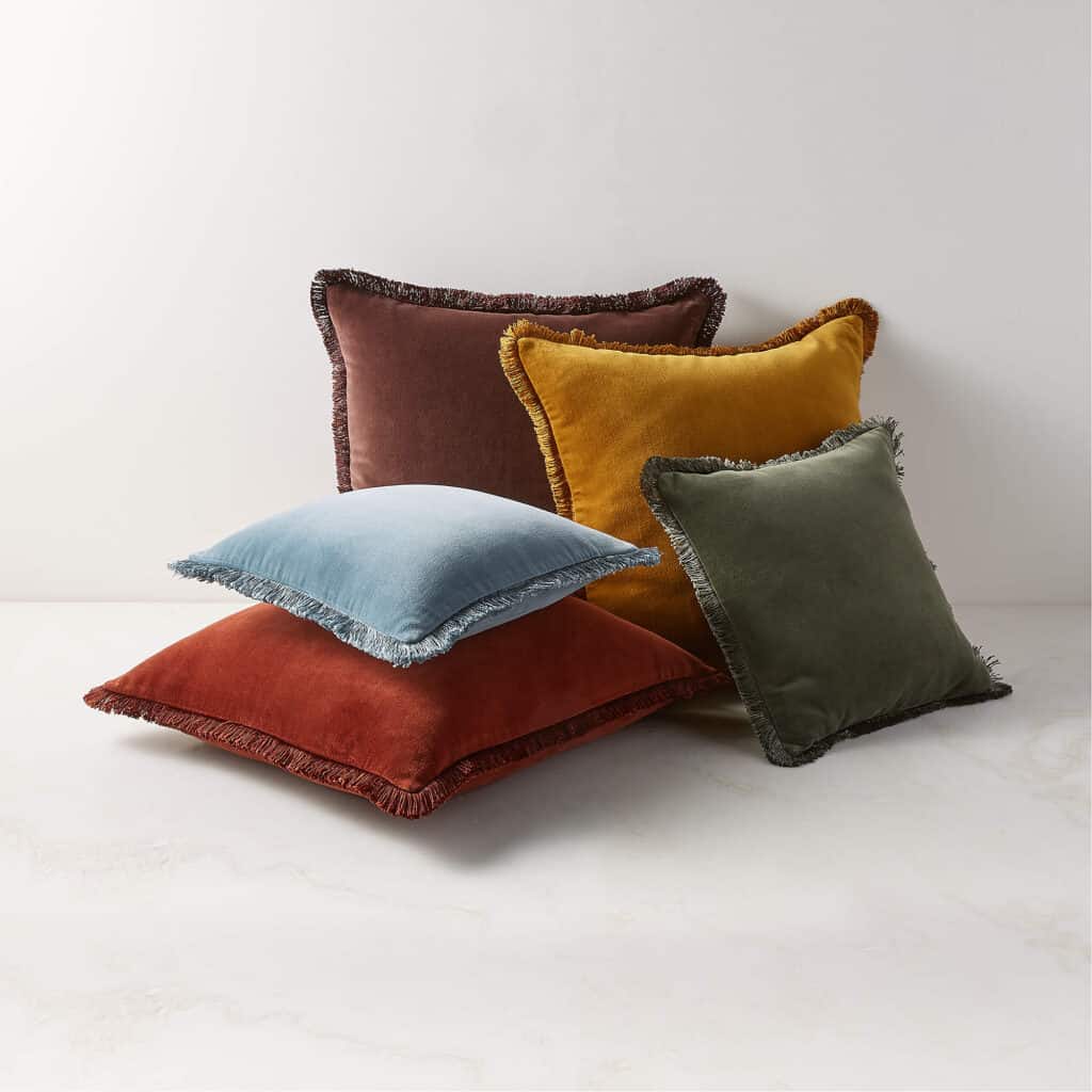 Five colorful throw pillows with fringe.