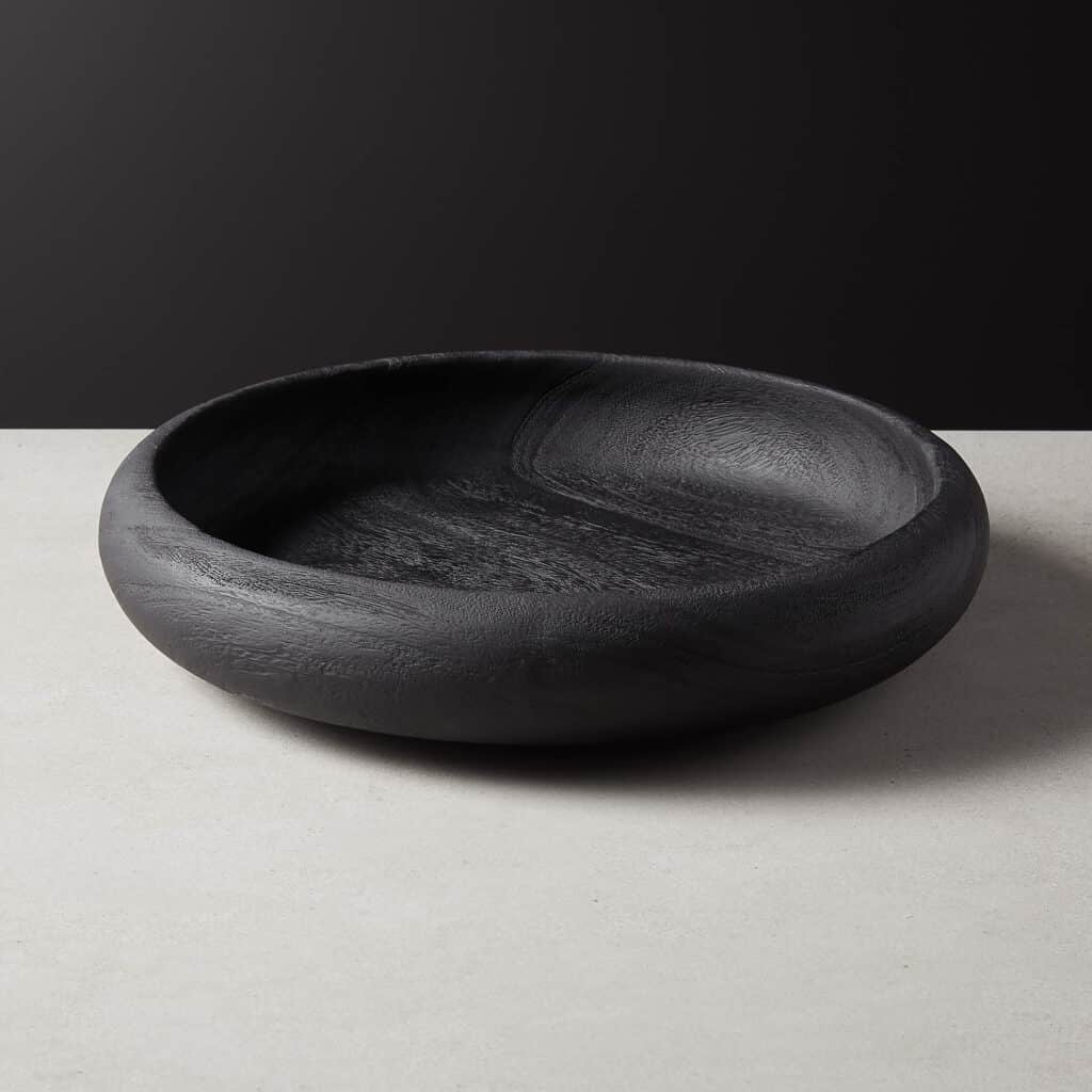 Black solid wood bowl on a table.