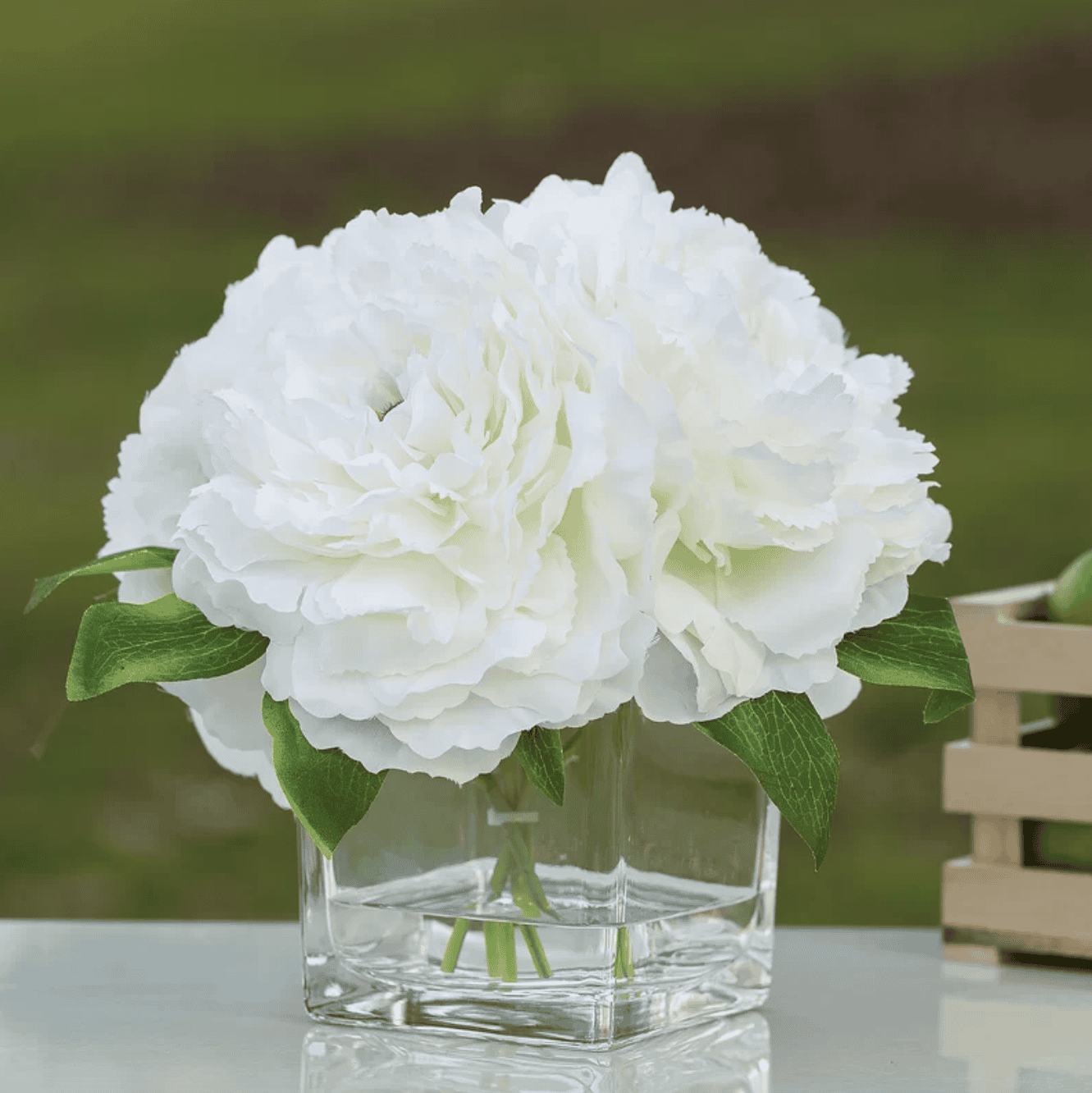 White silk peonies in a glass vase.
