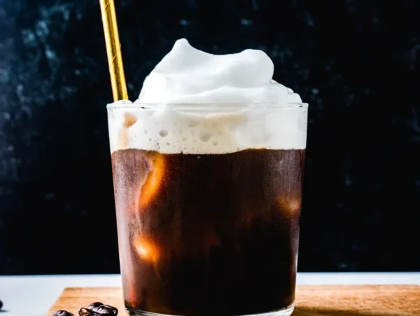 Golden paper straw in a coal foam iced coffee.