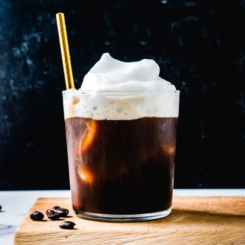 Golden paper straw in a coal foam iced coffee.