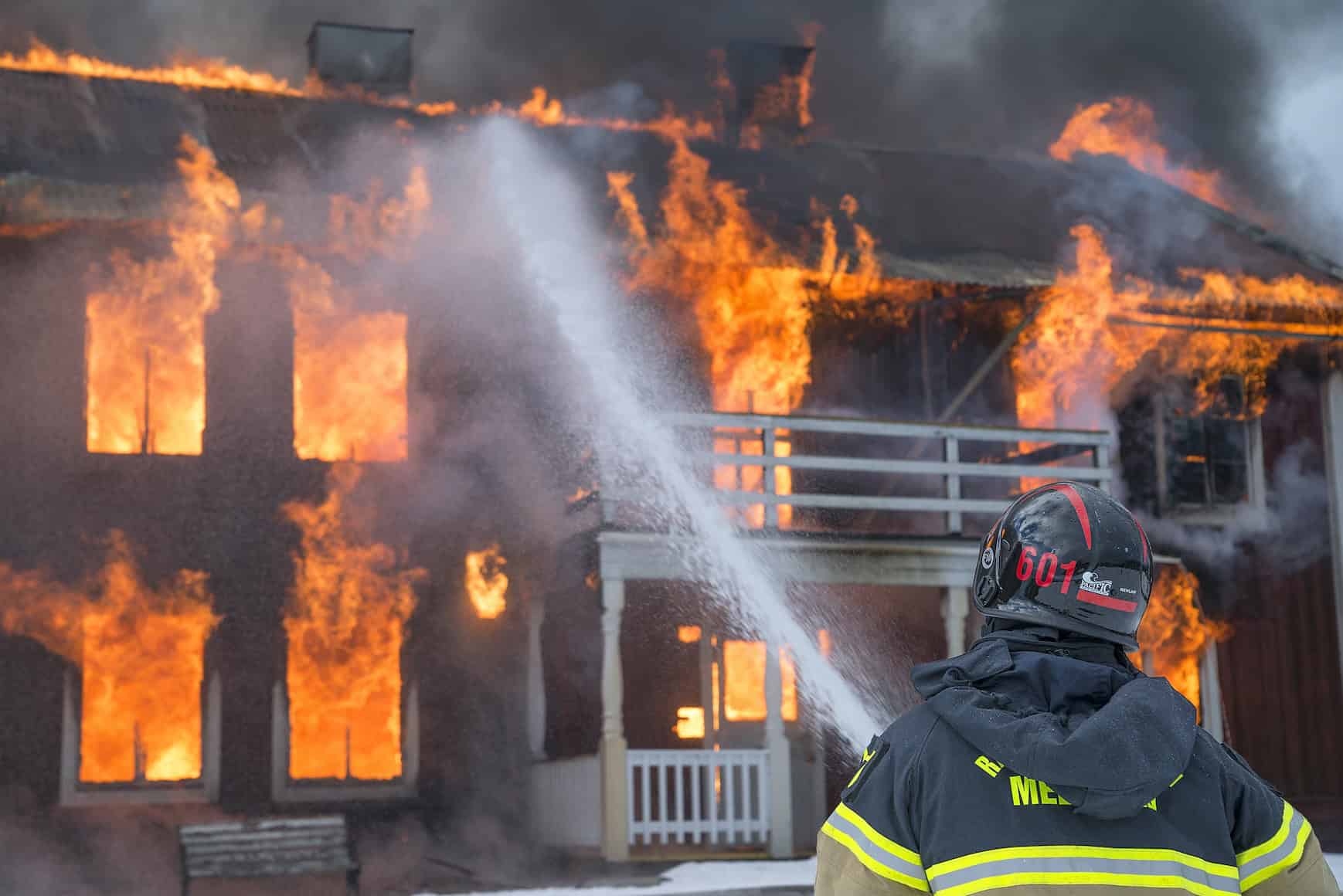 Firefighter spraying water on a burning building.