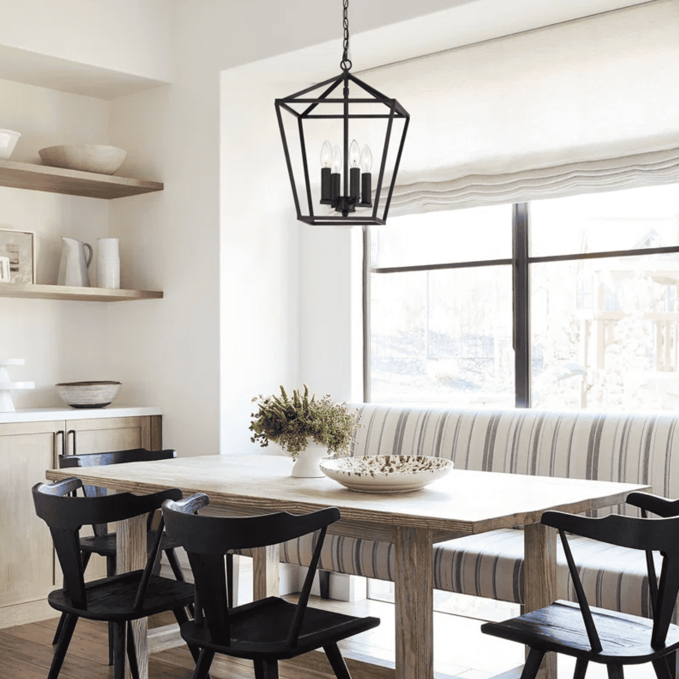 Black lantern chandelier hanging over a table.
