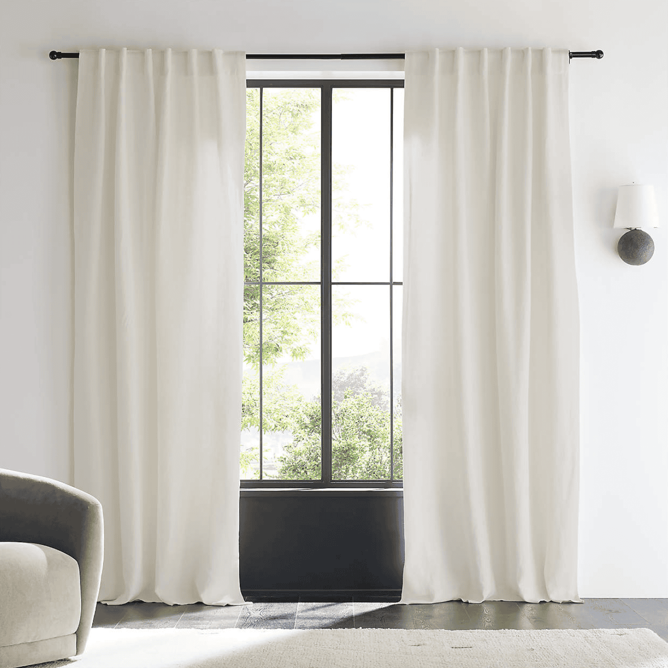 Linen curtains hanging in front of a bright window.