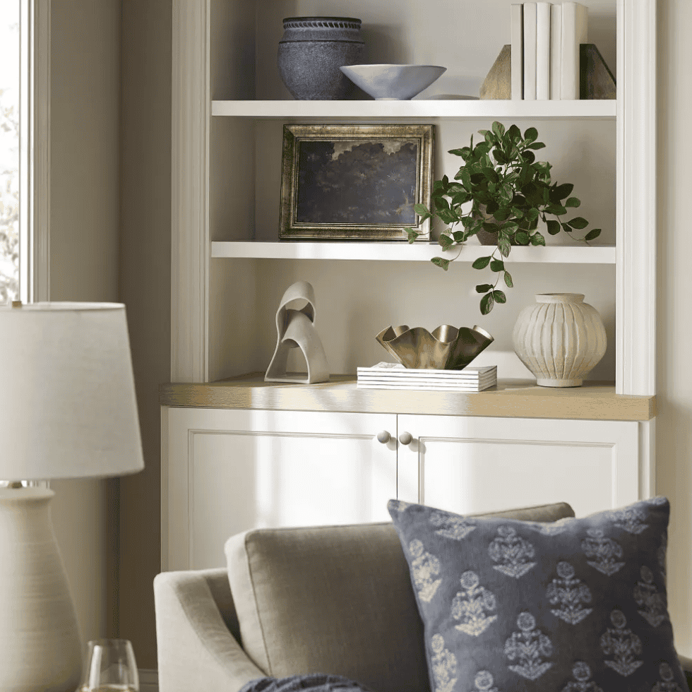 Shelf filled with different decorations including framed art of trees.