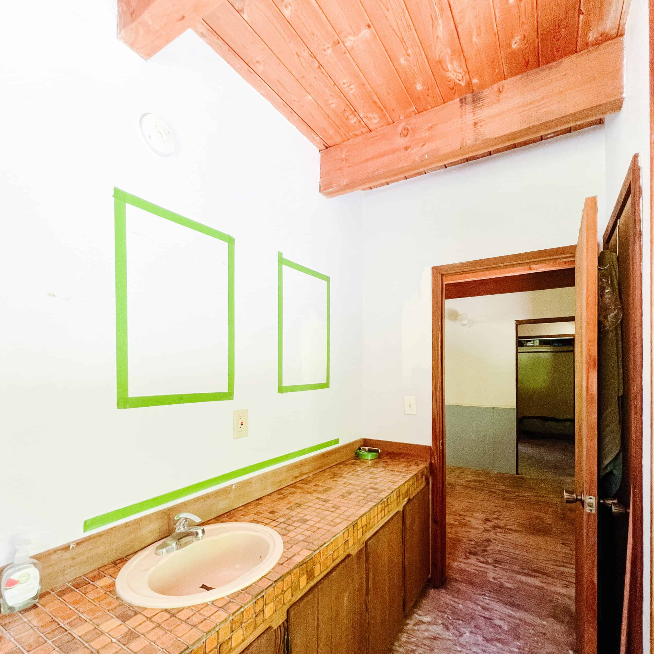 Green tape on the walls of an unfinished bathroom.