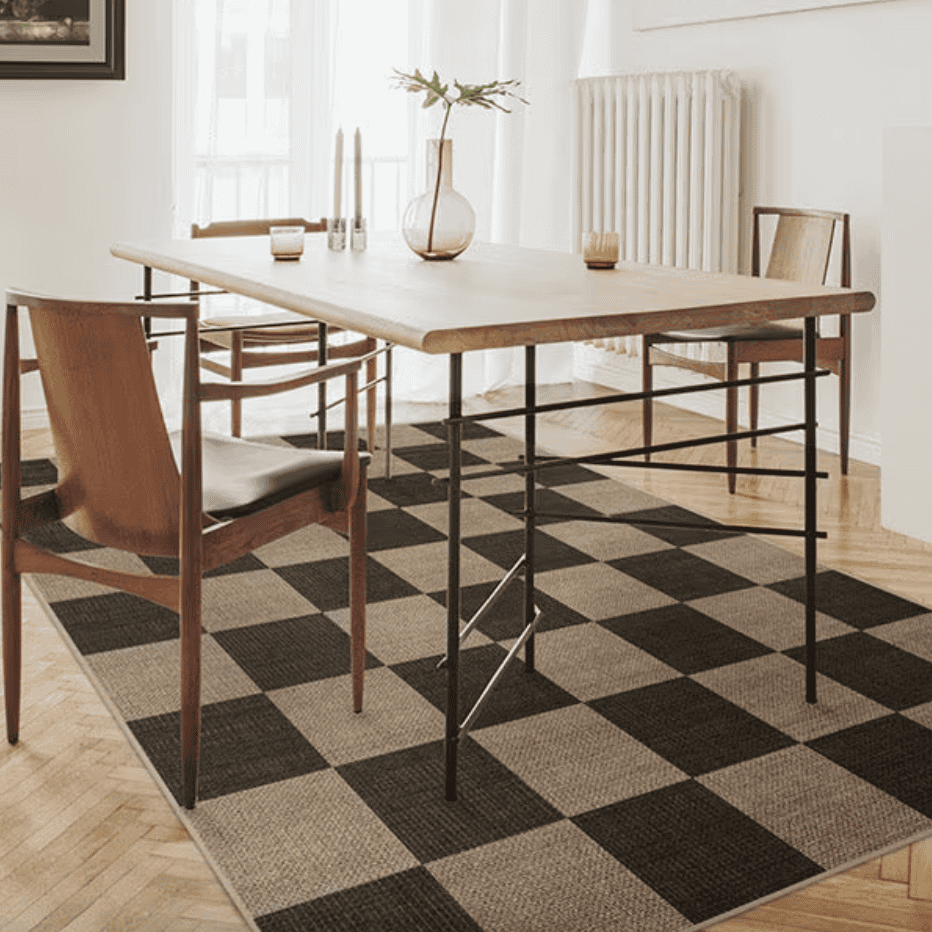 Dining table and chairs on a checkered rug.