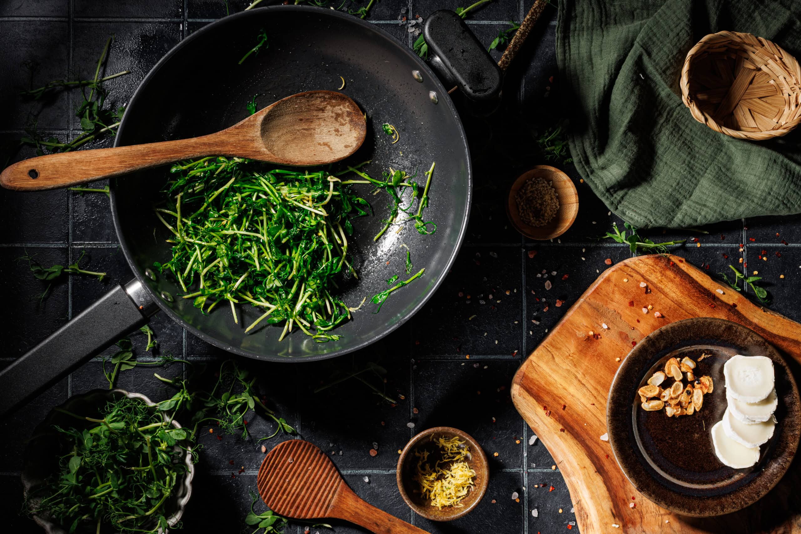 Pea shoots tossed with garlic-infused oil in a skillet, cooking until just wilted and bright green with a pinch of salt