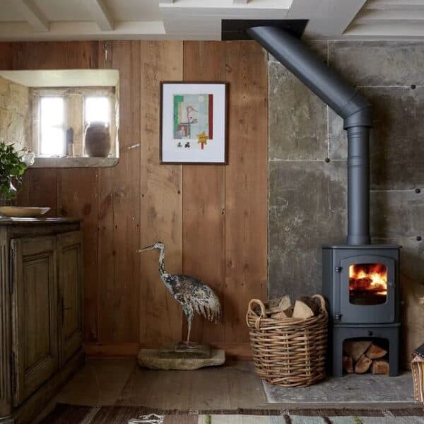 A wood burning stove in a room with a wooden wall