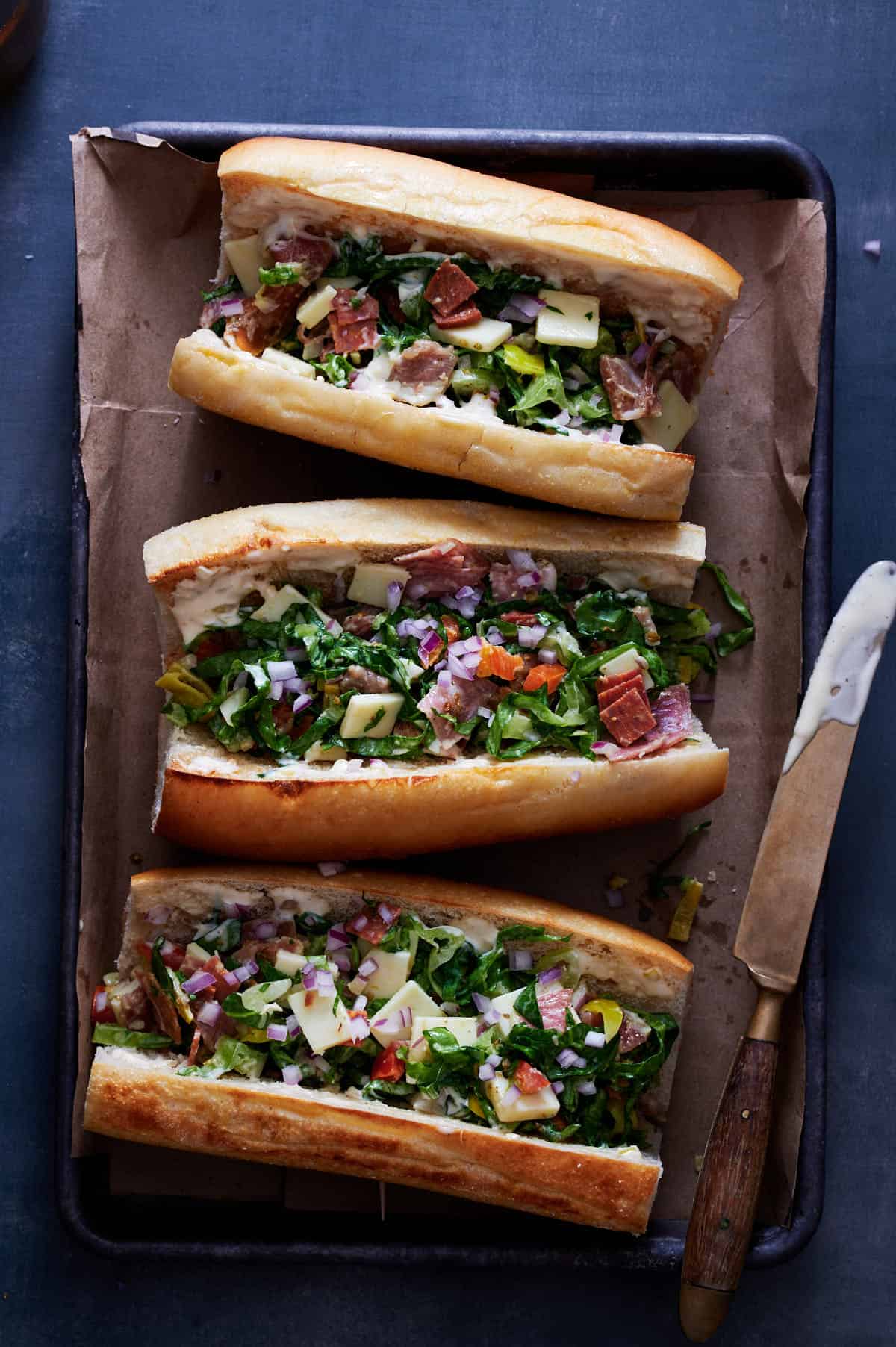 chopped Italian sandwich looking gorgeous on a metal tray with brightly colored vegetabls, meats and cheeses
