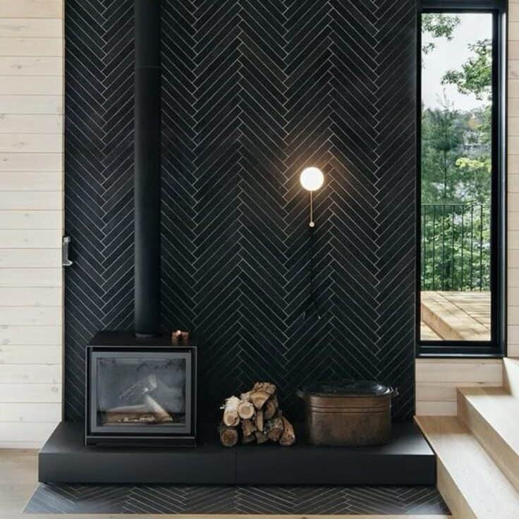 A modern wood burning stove on a black herring bone surrond that goes all the way up. 
