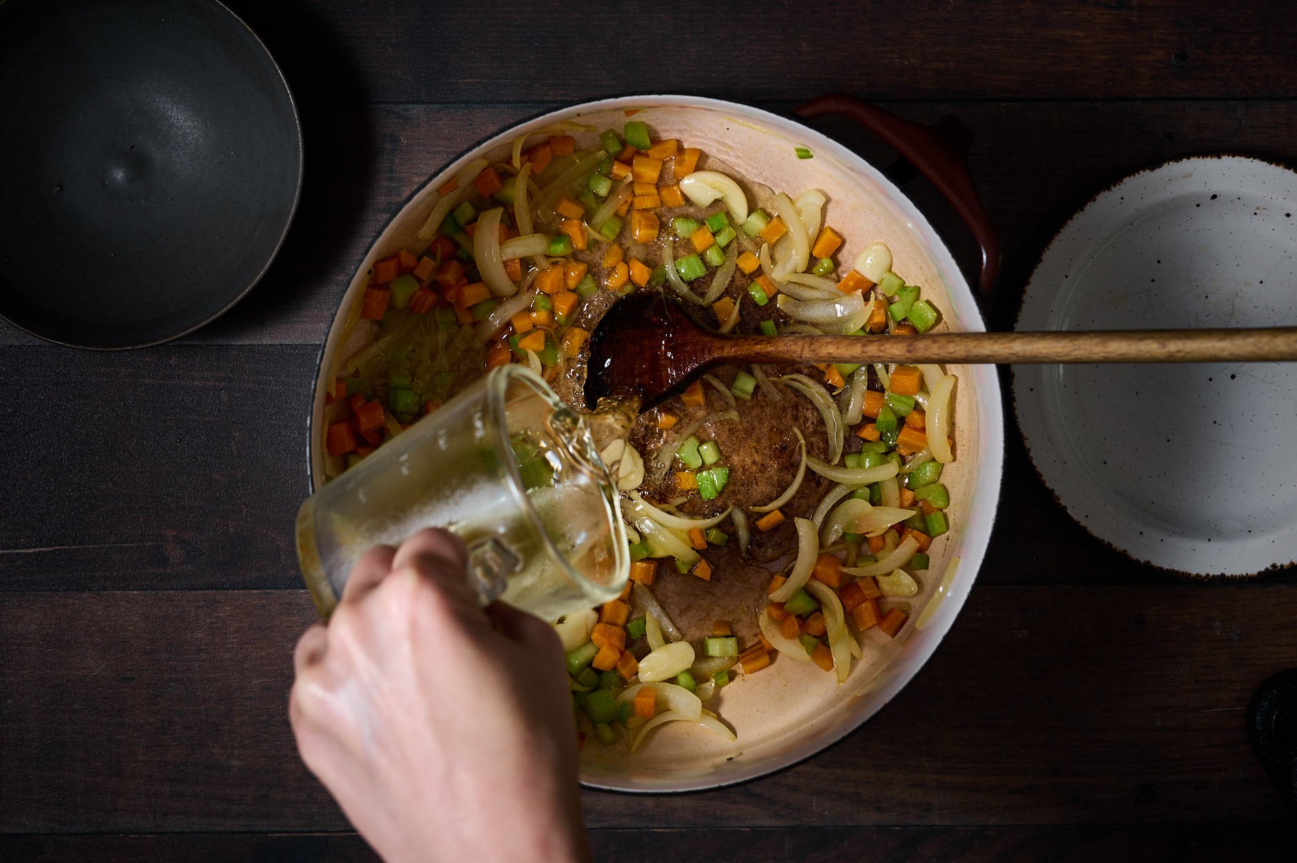 Adding white wine to a crock pot of sauteed vegetables to deglaze the pan for Pollo alla cacciatora.
